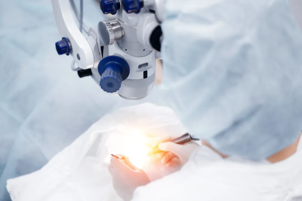Eye surgery using a surgical microscope Surgeon performing eye surgery using an operating microscope in a sterile surgical setting
