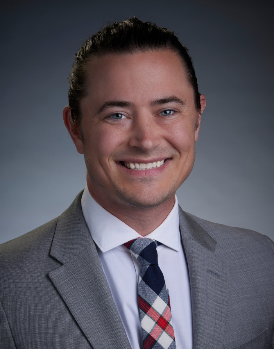 Dr. Eric J. Niespodzany - Pacific Clear Vision Eugene Professional headshot of Dr. Eric J. Niespodzany, an ophthalmologist, wearing a light gray suit, white shirt, and plaid tie, smiling against a neutral gradient background. - Pacific Clear Vision Eugene