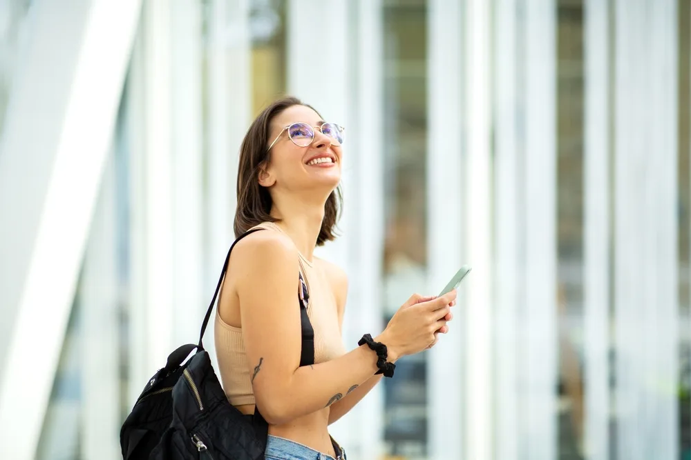 Considering LASIK to reduce dependence on glasses Woman wearing glasses smiling outdoors while considering LASIK vision correction
